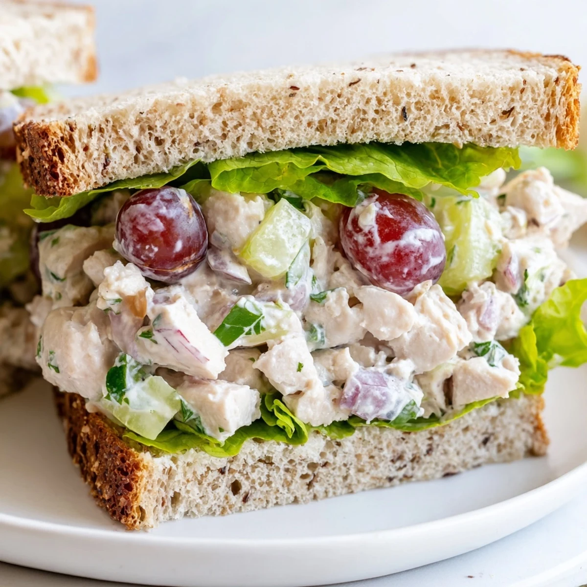 A plated Chicken Salad Sandwich with Grapes served on whole wheat bread, perfect for a refreshing American lunch.