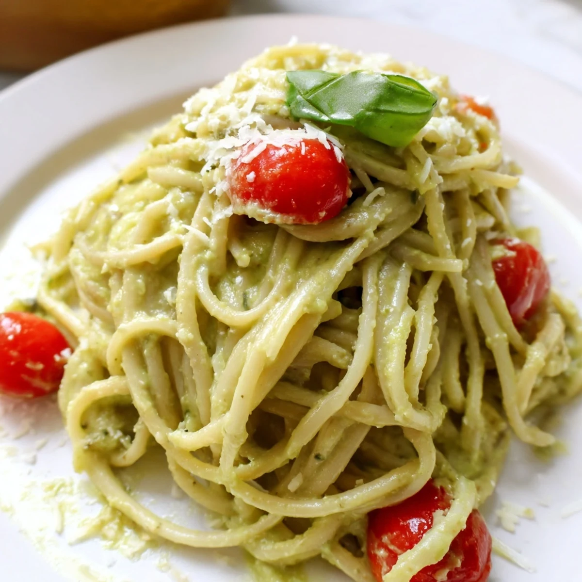 Creamy Avocado Lime Pasta with Cherry Tomatoes served in a white bowl, topped with extra Parmesan and cracked black pepper.