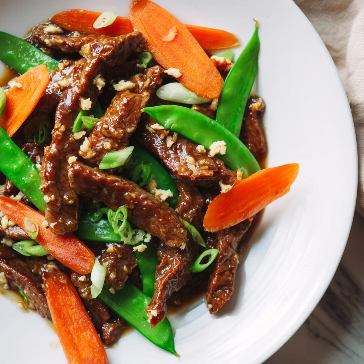 Freshly cooked beef stir fry with snow peas, carrots, and ginger garnished with green onions, ready for a family dinner.