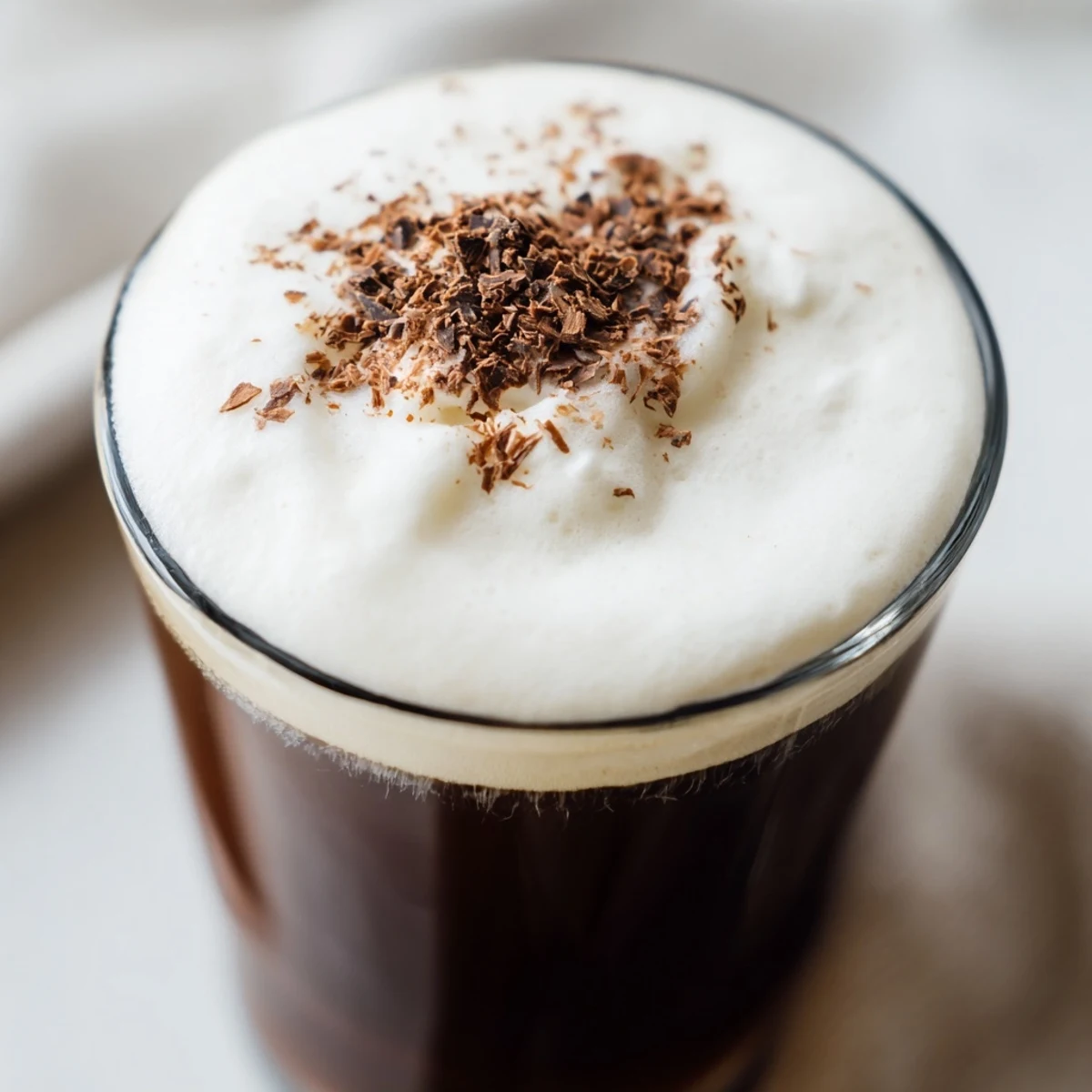 Non-alcoholic Irish Coffee Mocktail garnished with dark chocolate shavings alongside cinnamon-dusted shortbread for a perfect café-style sip.