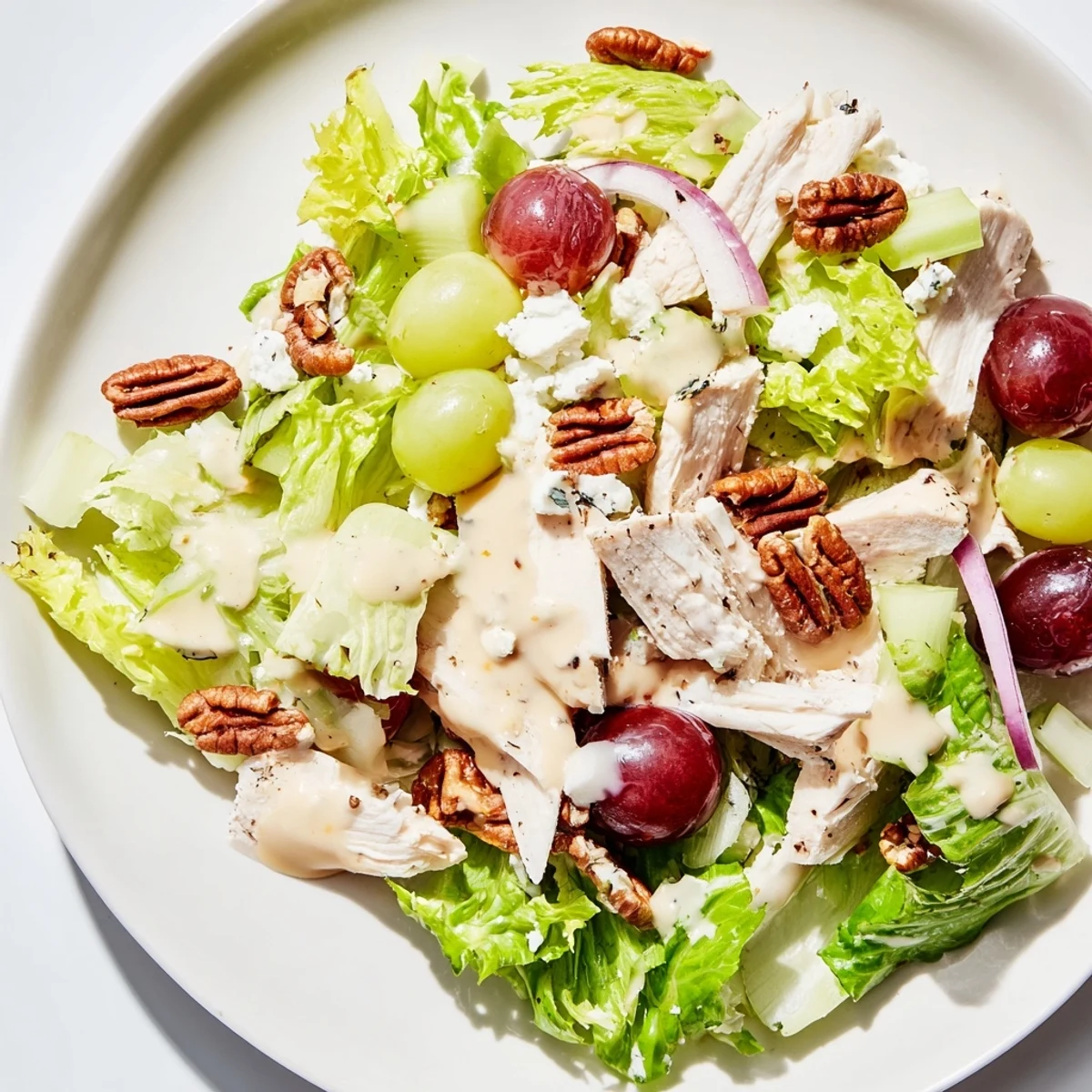 For a light lunch, enjoy this hearty American Chicken Pecan Salad with Dressing, drizzled with smooth dressing and garnished with celery slices.