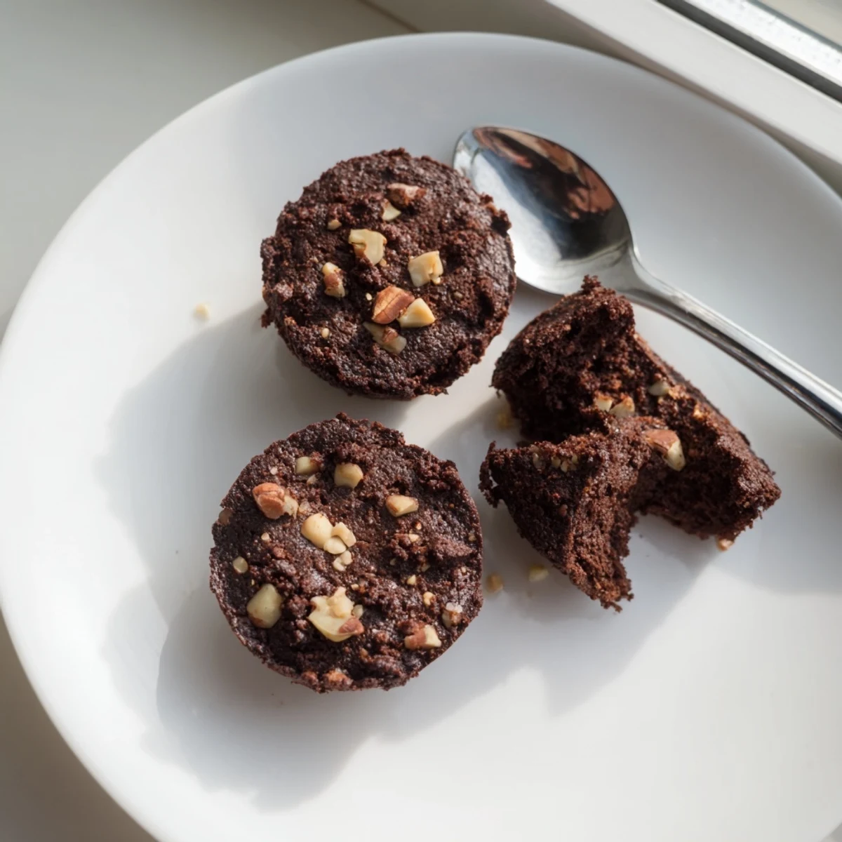 Fudgy Chocolate Brownie Bites with nuts on a marble counter, with a glass of cold milk nearby.