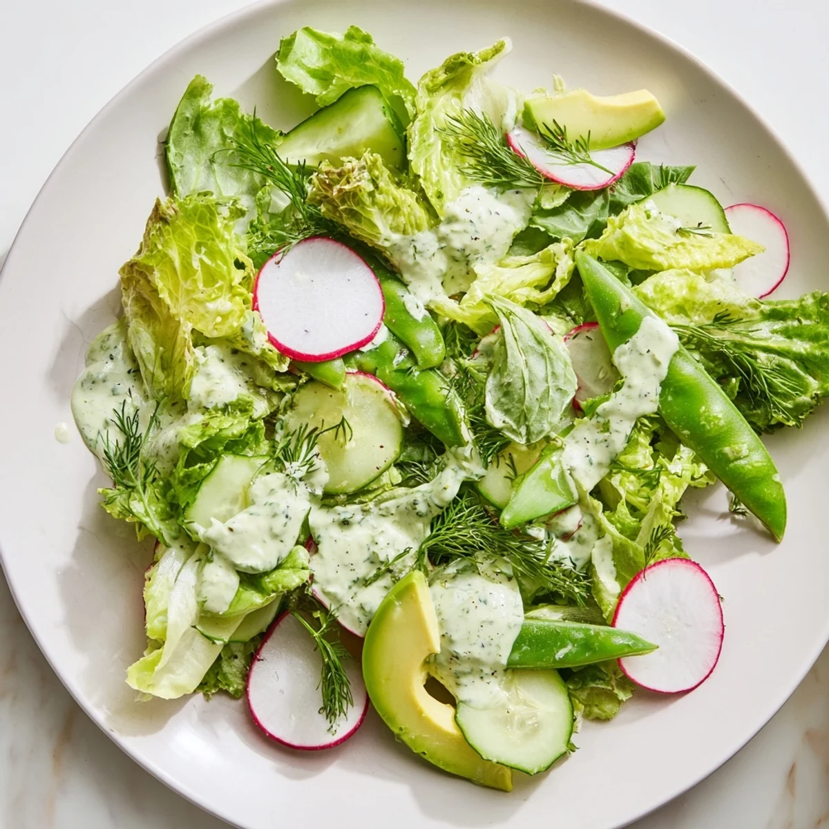 Freshly tossed Green Salad with Green Goddess Dressing showcases tender butter lettuce, sugar snap peas, and chopped herbs in a refreshing, colorful presentation.  