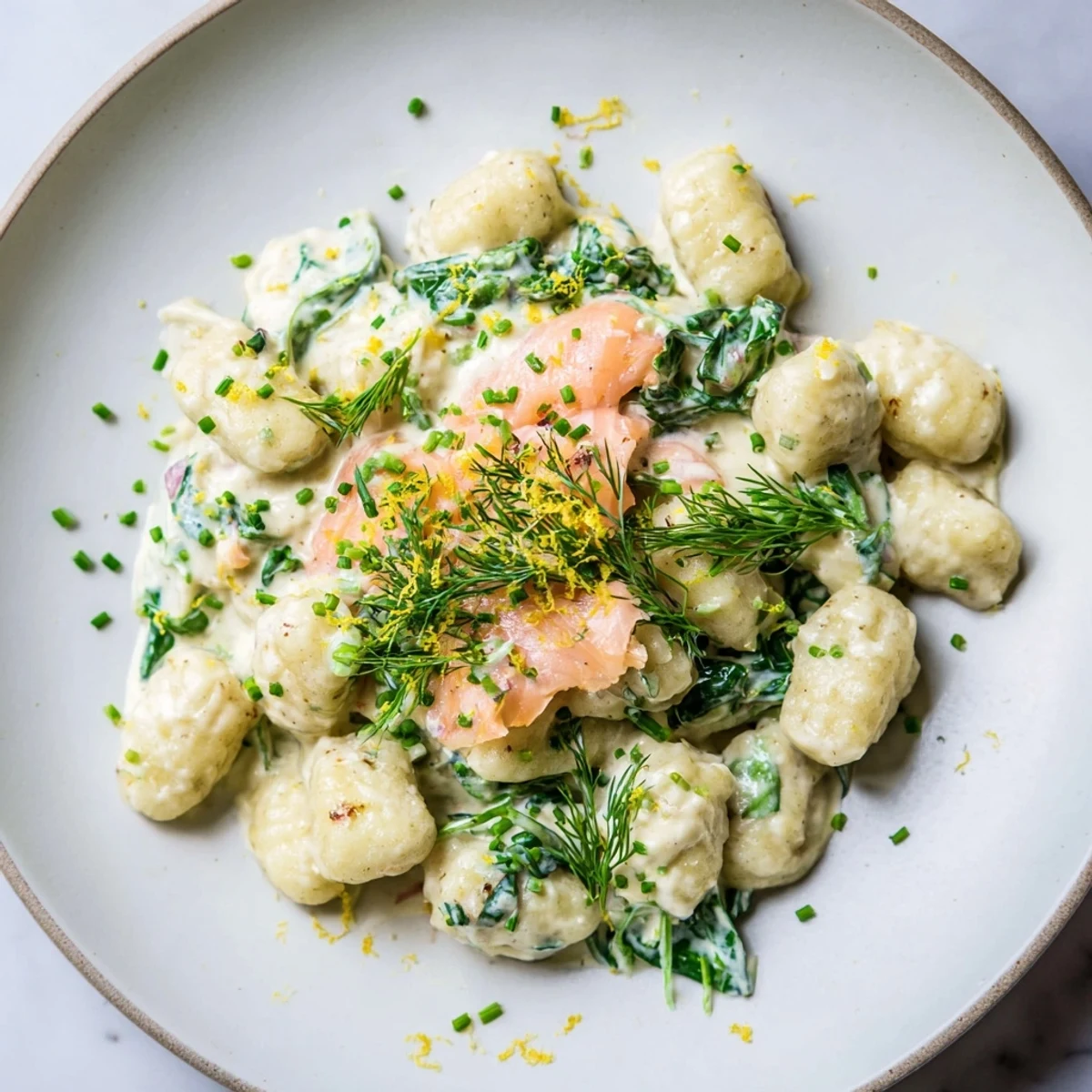 A close-up of Healthy Smoked Salmon Gnocchi highlighting tender salmon strips and wilted spinach in a creamy sauce.