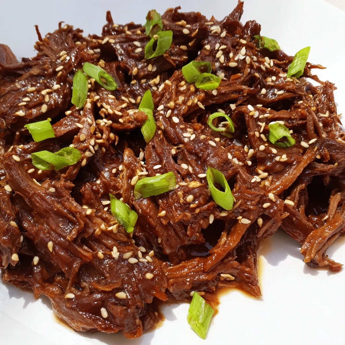 Tender shredded Crock Pot Korean Beef simmered in savory-sweet sauce, served over fluffy jasmine rice with sesame seeds.