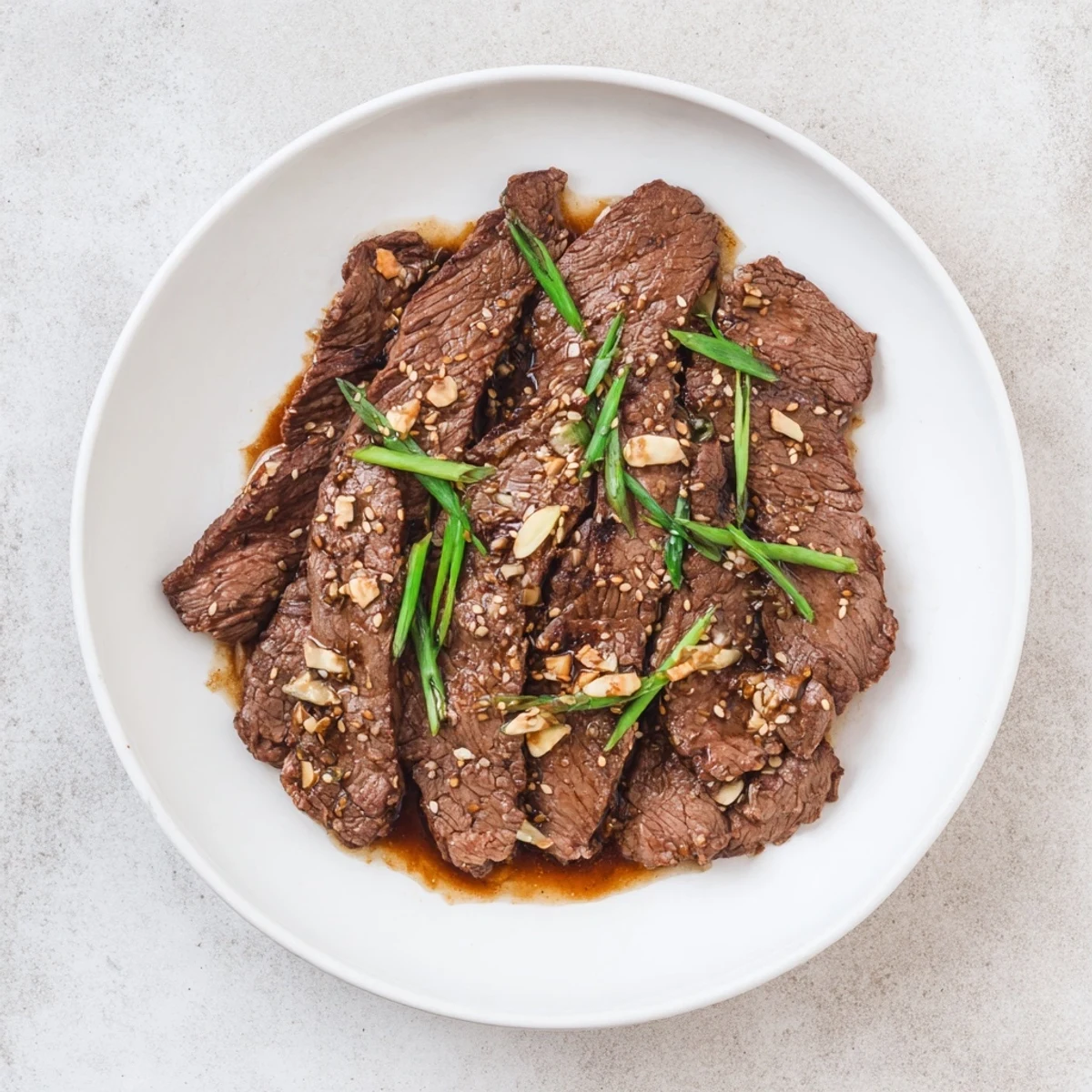A close-up of Ultimate Slow Cooker Mongolian Beef, showcasing melt-in-your-mouth beef, glistening sauce with garlic and ginger, and a garnish of sesame seeds.