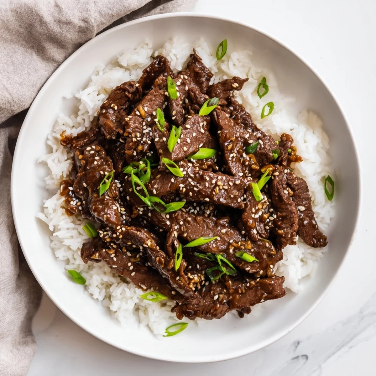 Slow cooker Ultimate Mongolian Beef with tender beef slices and rich sauce over fluffy white rice.