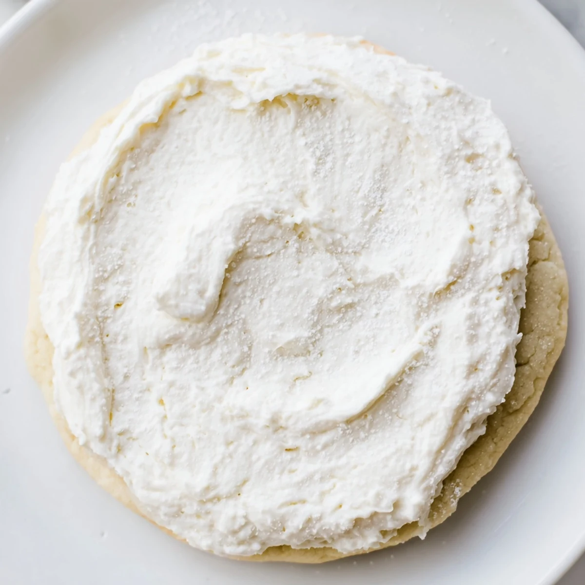 A spatula lifts Easy Sugar Cookie Frosting with a slight crust, perfect for decorating frosted sugar cookies in a home kitchen.