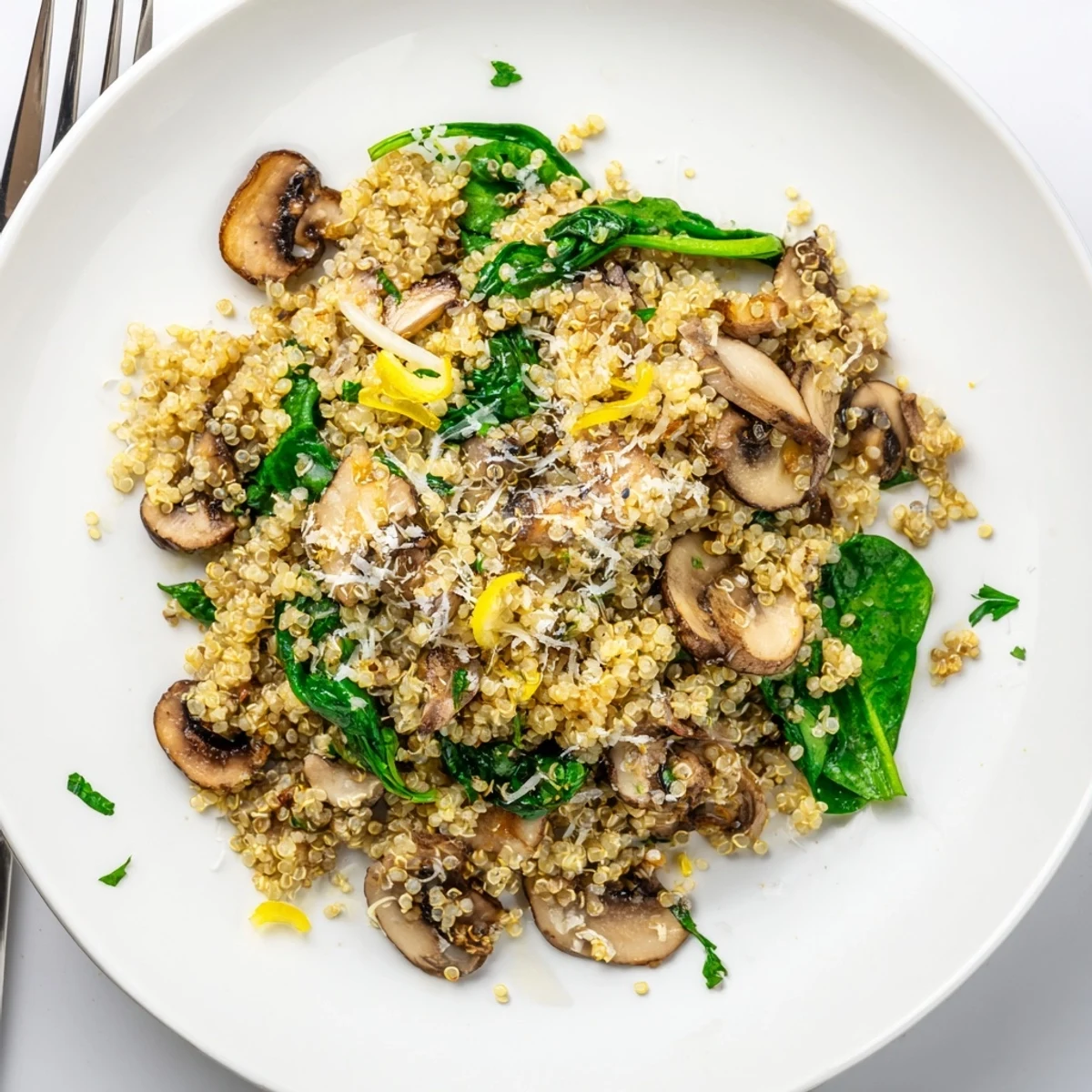 A steaming skillet of Garlicky Mushroom Quinoa showcases golden-brown mushrooms and wilted spinach, ready to be served as a hearty vegetarian main.