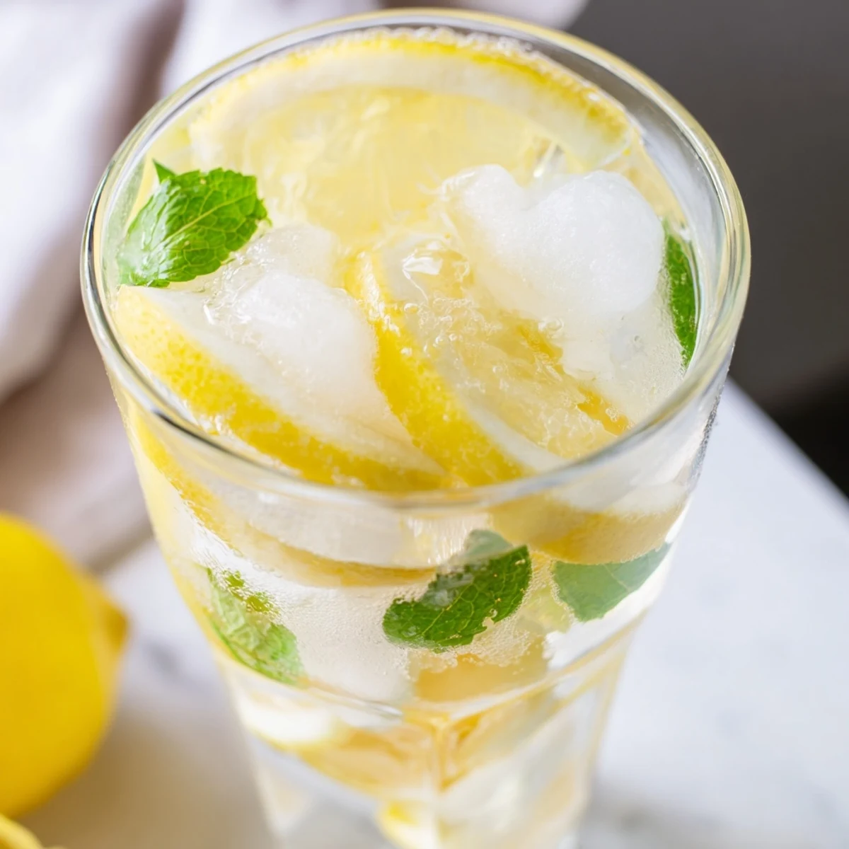 Two glasses of Easy Limoncello Mocktail Refreshing Drink over ice, garnished with fresh mint and lemon slices.
