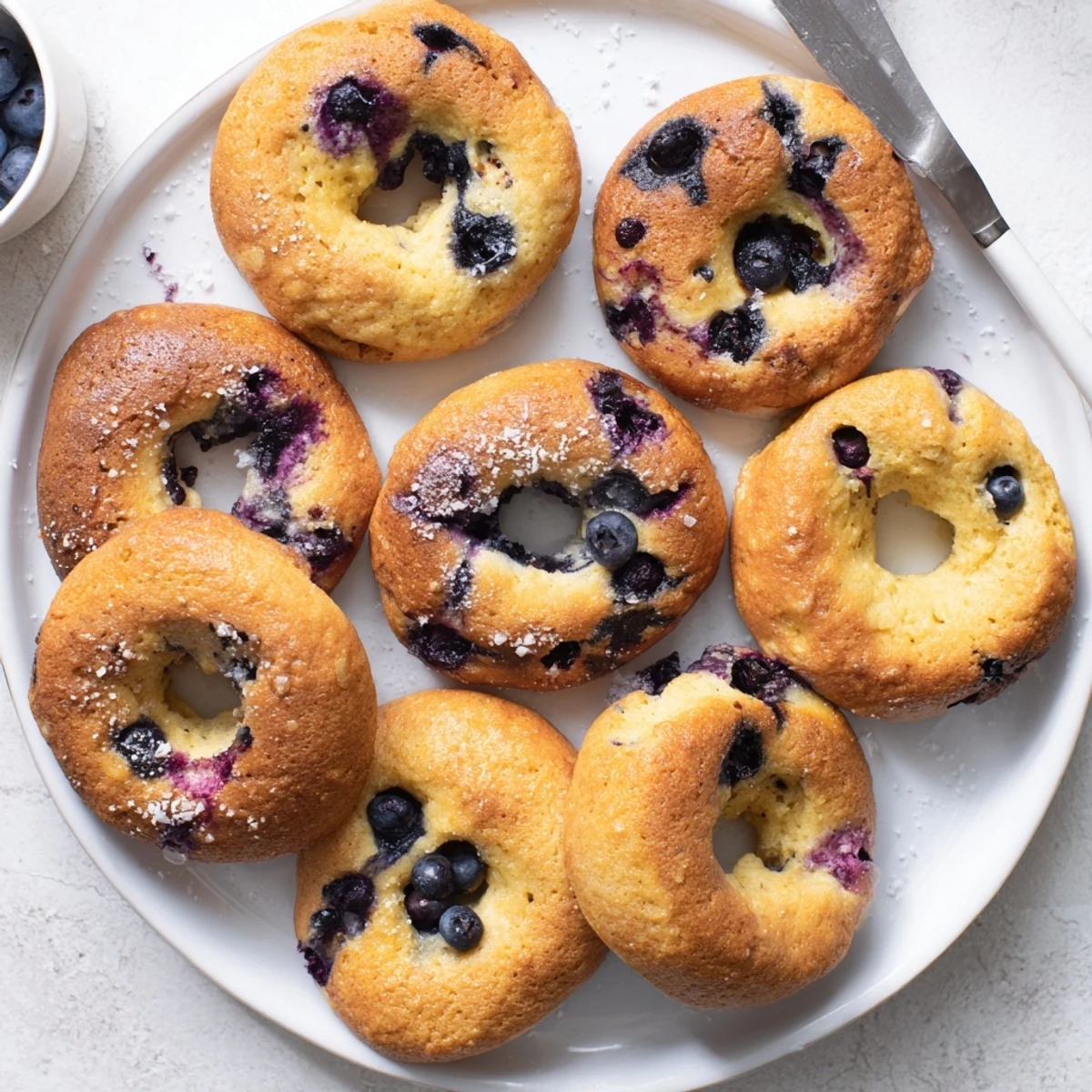 Gluten-Free Blueberry Bagels are displayed sliced, showing a soft, chewy interior studded with plump blueberries.  