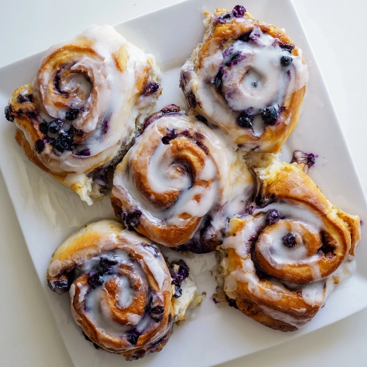 Freshly baked Blueberry Cinnamon Rolls topped with creamy vanilla glaze.
