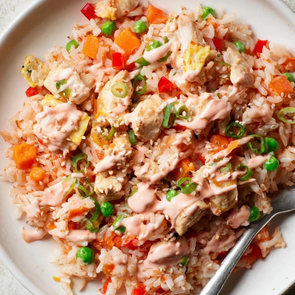 Plated Bang Bang Fried Rice topped with fresh green onions, served alongside a small bowl of extra sauce.