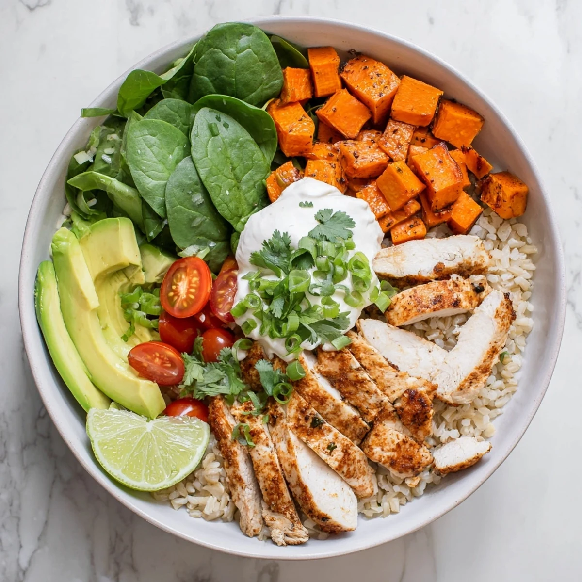 The wholesome chicken sweet potato rice bowl features juicy grilled chicken, tender roasted sweet potatoes, and fluffy rice topped with cherry tomatoes and Greek yogurt.
