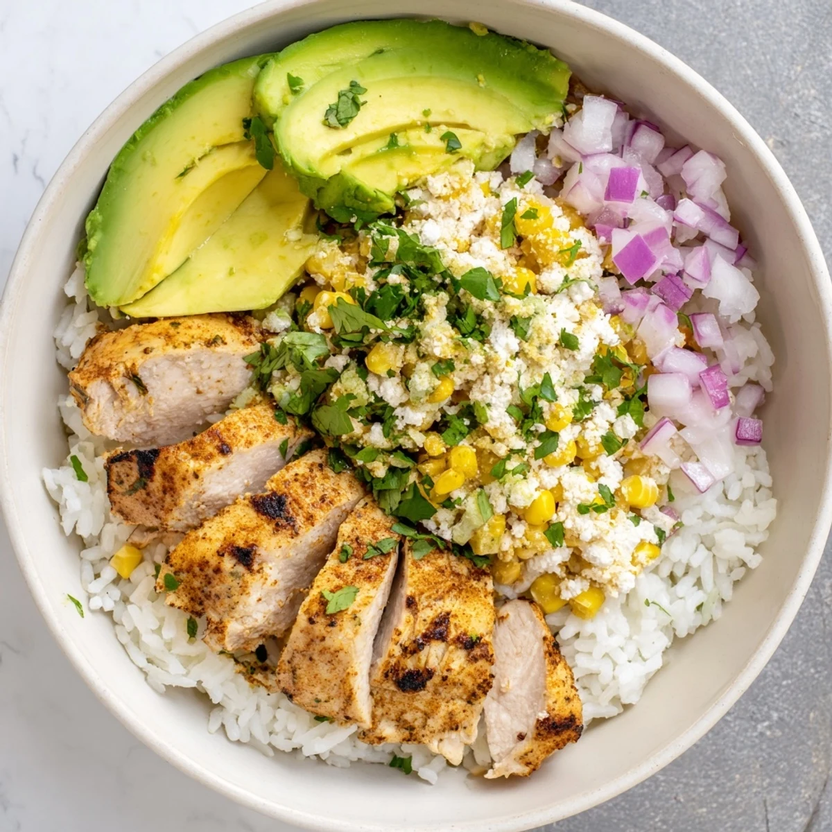 Grilled chicken and zesty street corn rice bowl topped with avocado and fresh cilantro for a vibrant Mexican-inspired meal.