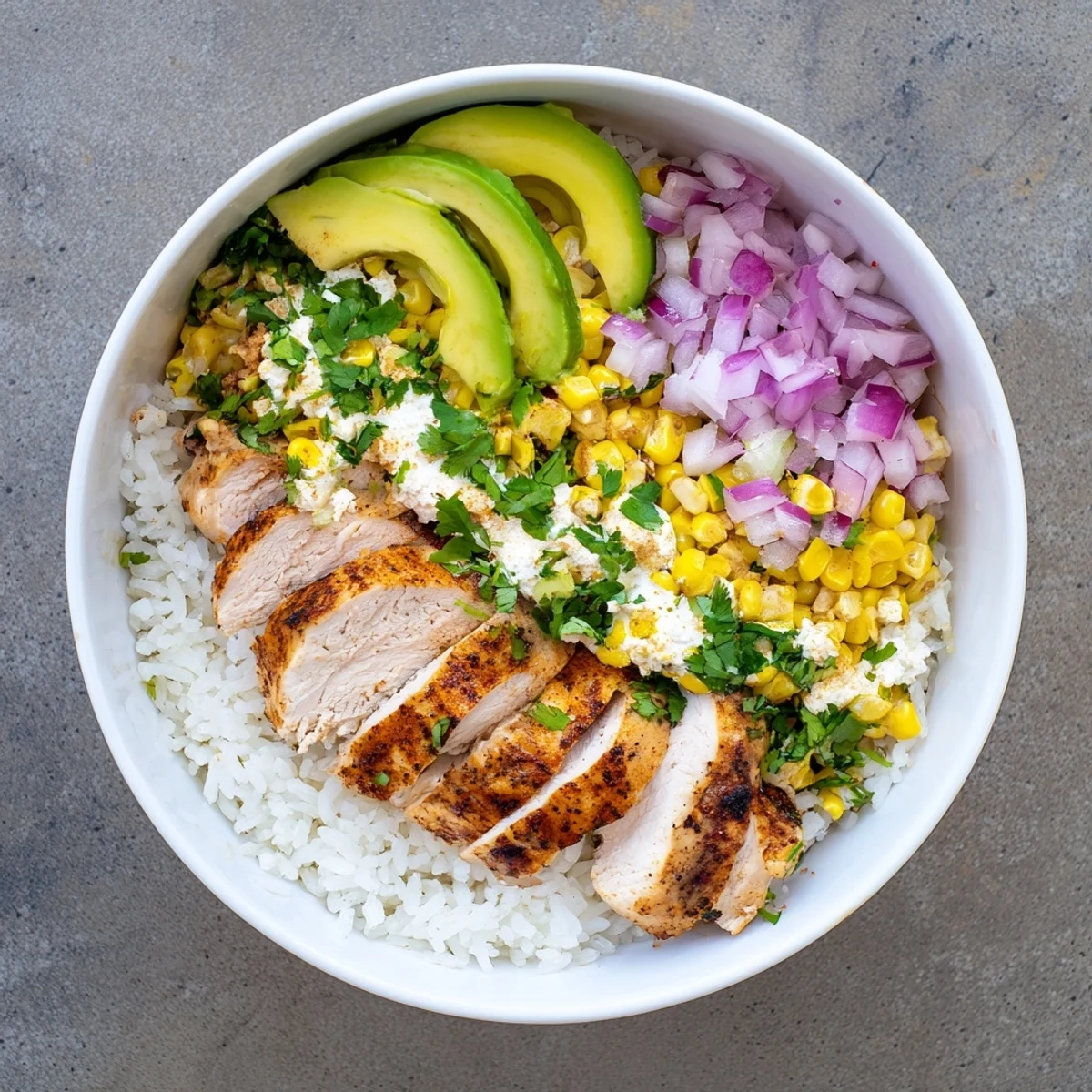 A hearty Street Corn Chicken Rice Bowl with lime wedges, red onion, and creamy toppings, ready for a quick dinner.