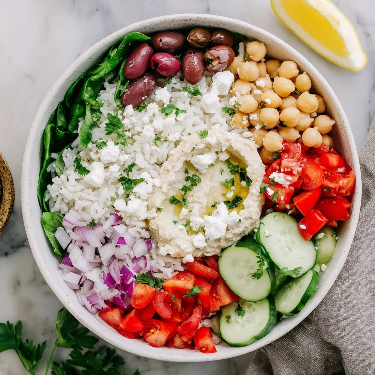 Fluffy rice Mediterranean bowl arranged with fresh cherry tomatoes, cucumber, olives, and creamy feta