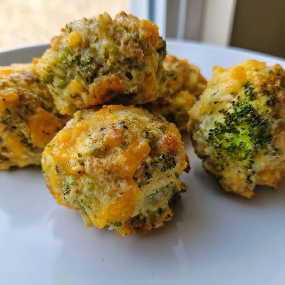 Crispy baked broccoli and cheese balls displayed on a wooden board with dip
