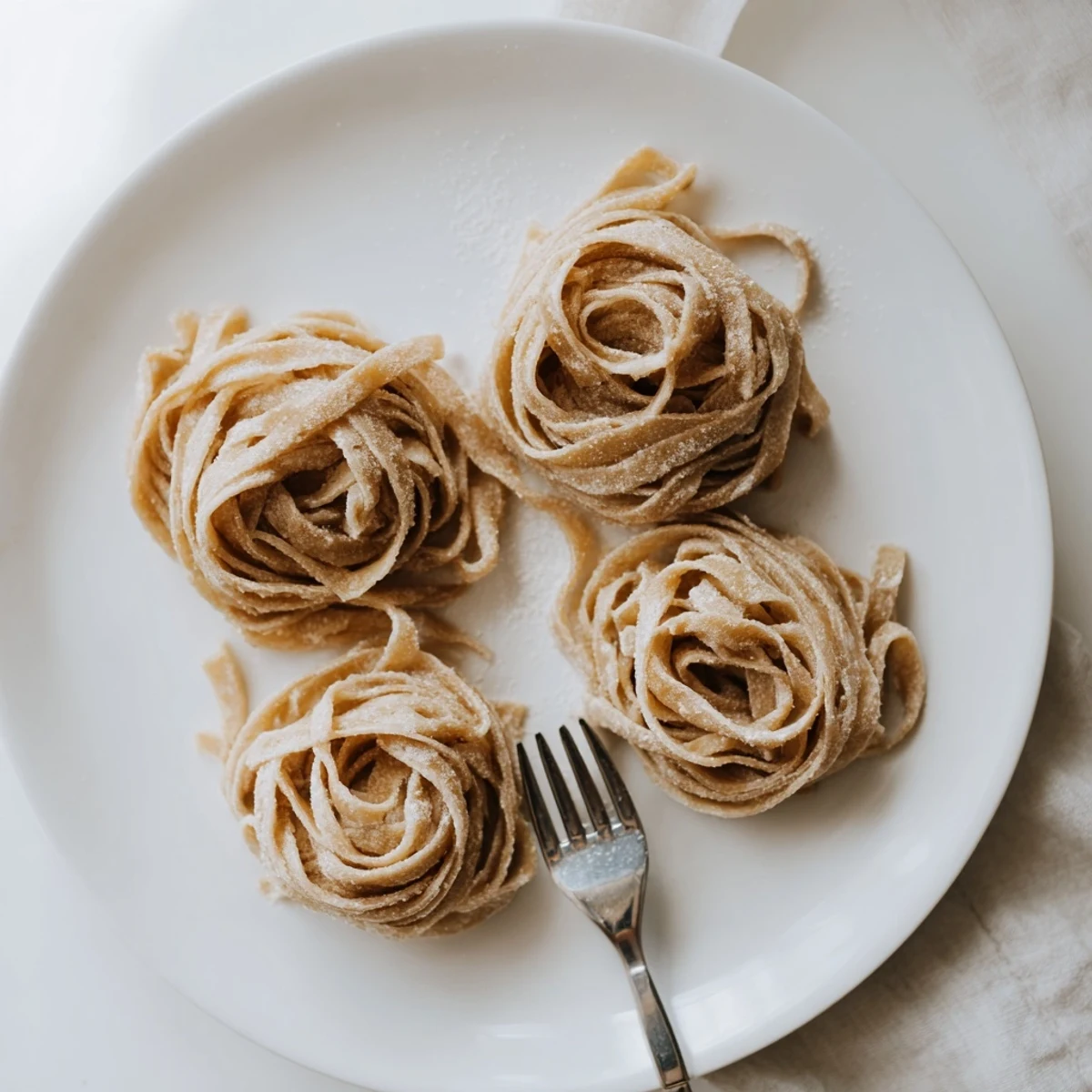 Golden strands of homemade sourdough pasta dusted with flour on a wooden cutting board