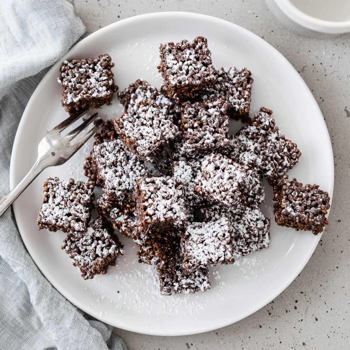 Baked tray of Muddy Buddy Rice Krispies cut into squares with powdered sugar coating
