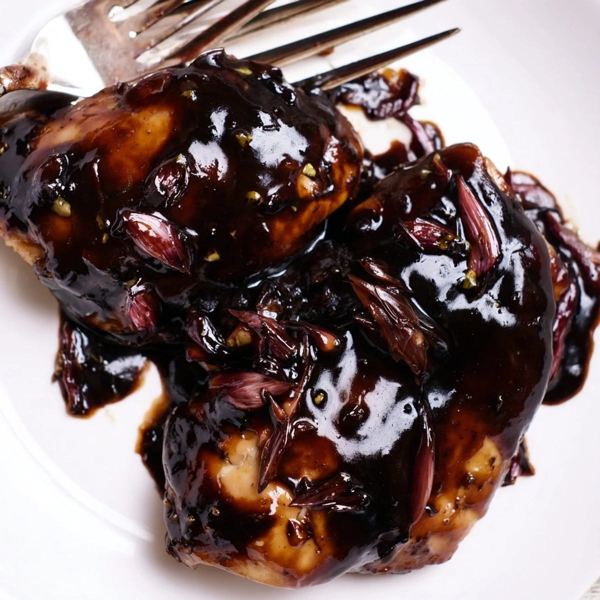 Succulent slow cooker balsamic chicken pieces coated in sweet and savory dark sauce with sliced red onions