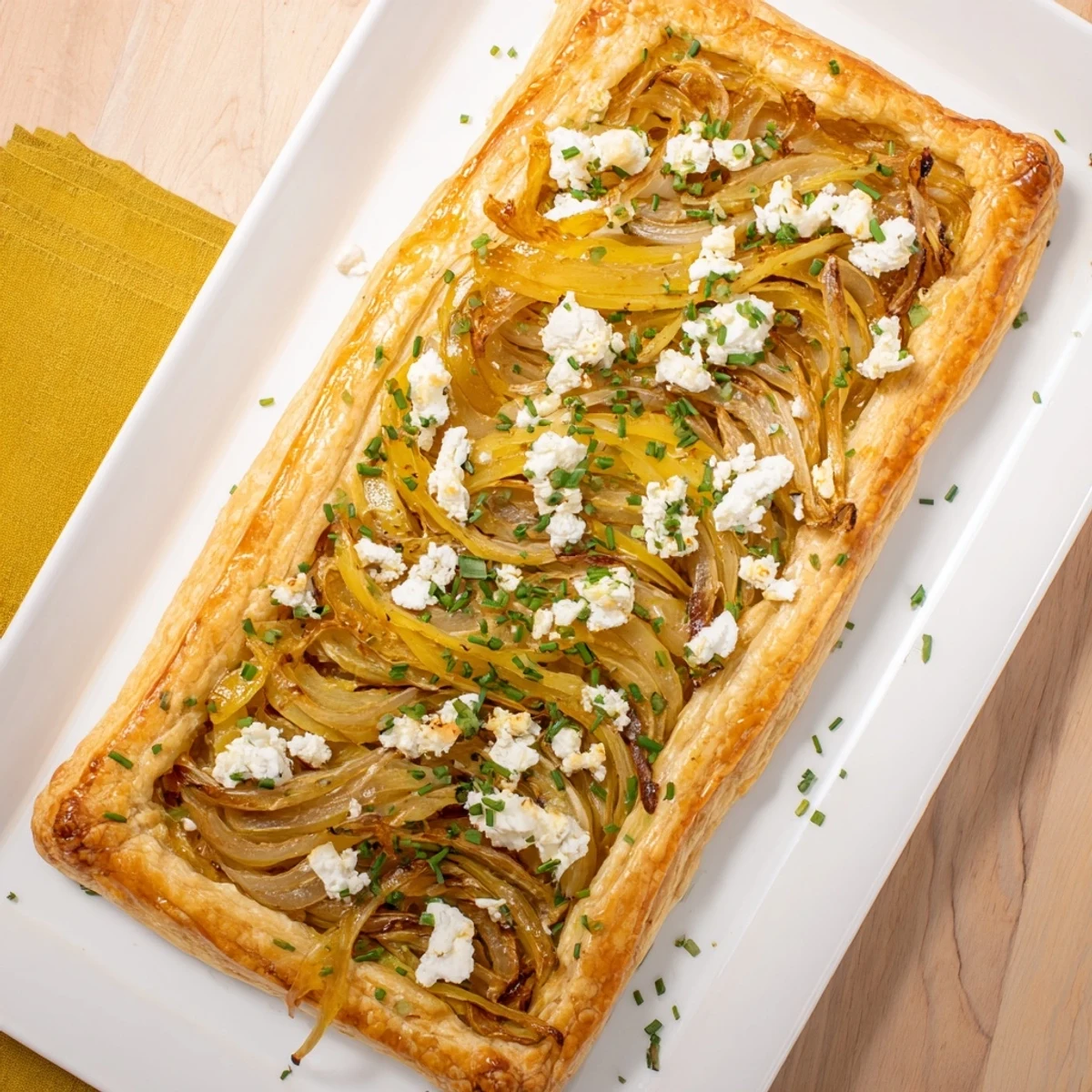 Golden caramelized onion and goat cheese tarts on flaky puff pastry with fresh herbs