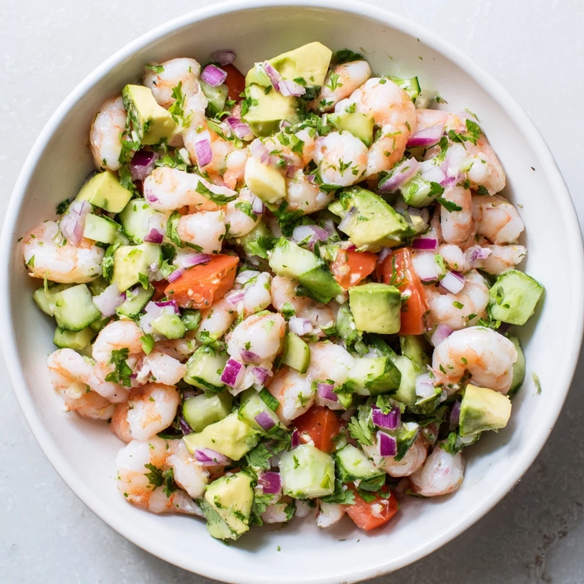 Glass bowl of zesty easy shrimp ceviche marinated in citrus with diced avocado, tomato, and cucumber