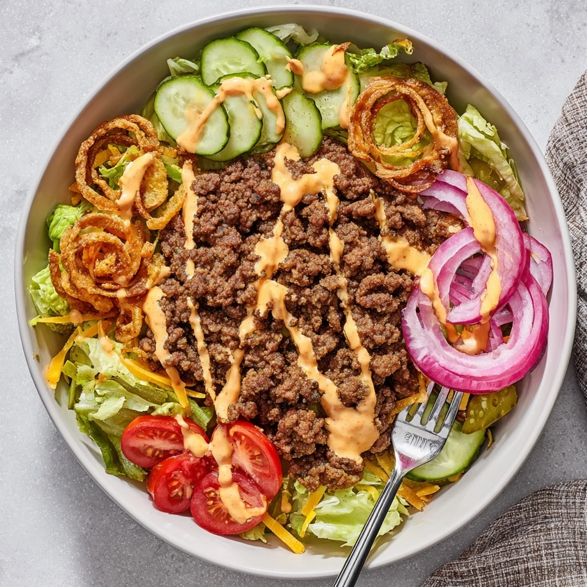 Golden crispy smash burger patties arranged over fresh salad greens with colorful vegetables in a bowl