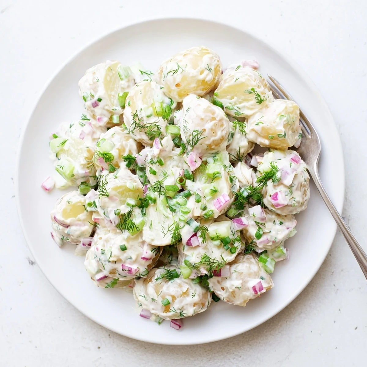 Healthy Greek yogurt potato salad tossed with colorful vegetables and garnished with fresh parsley on a rustic wooden table