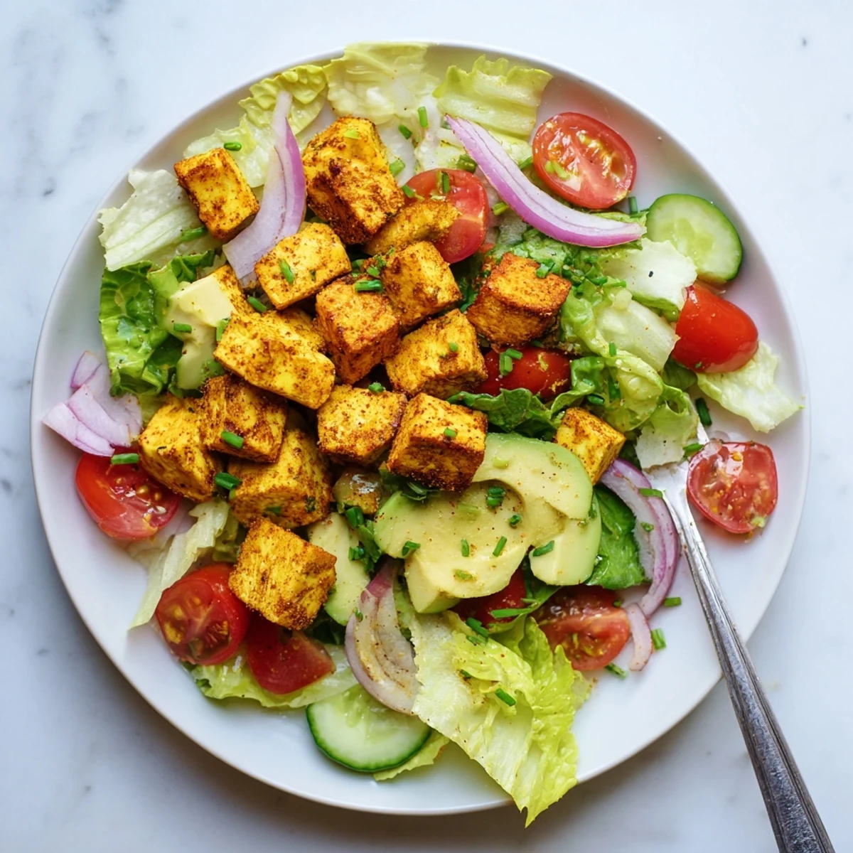 Golden smoky tofu pieces arranged over crisp green lettuce and juicy red tomato slices