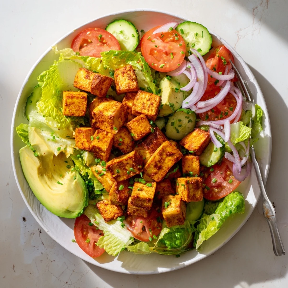 Vegan smoky tofu salad featuring crunchy romaine fresh avocado and warm seasoned tofu cubes