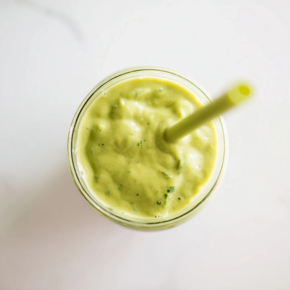 Thick green Greek yogurt avocado smoothie topped with fresh banana slices and chia seeds