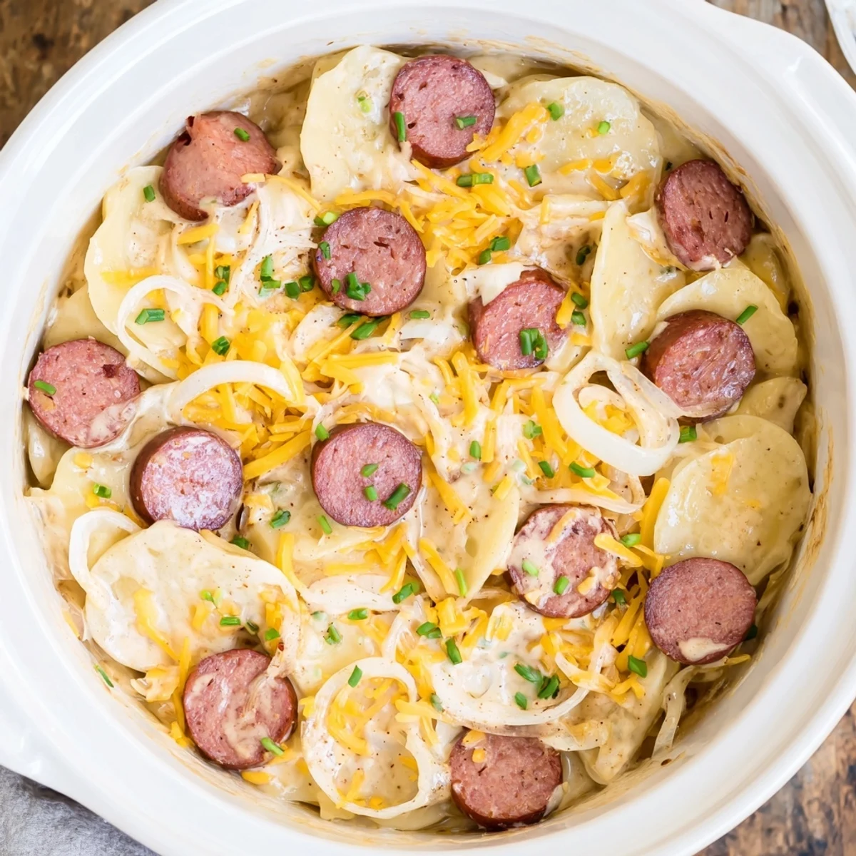 Crock Pot Pierogi Casserole with Kielbasa featuring bubbling cheddar cheese and sliced smoked sausage