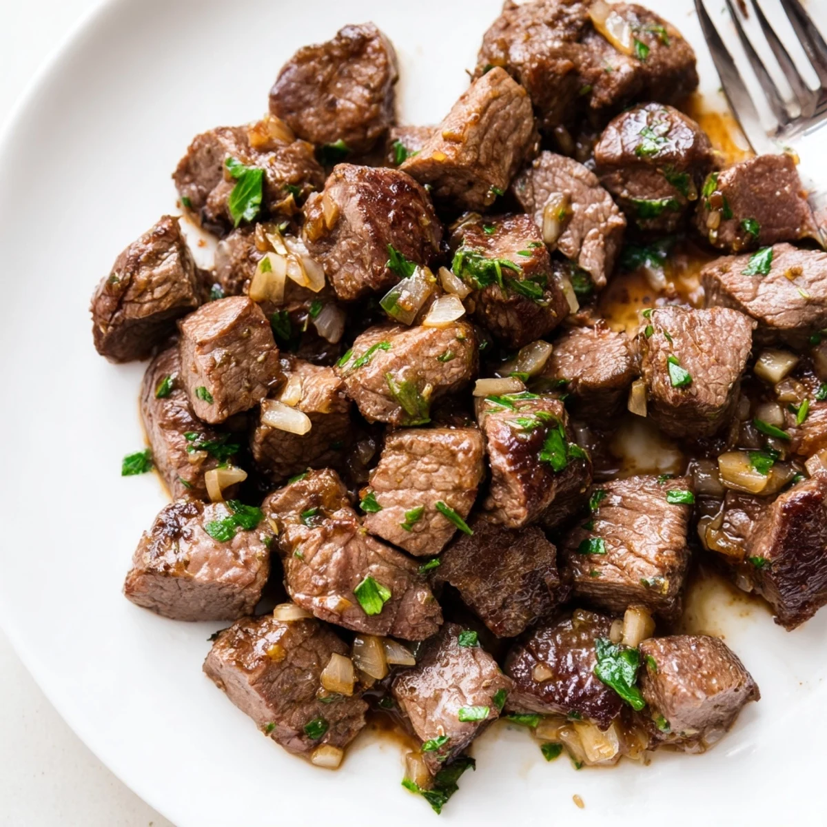 Tender crockpot steak bites swimming in garlic butter sauce with fresh parsley garnish