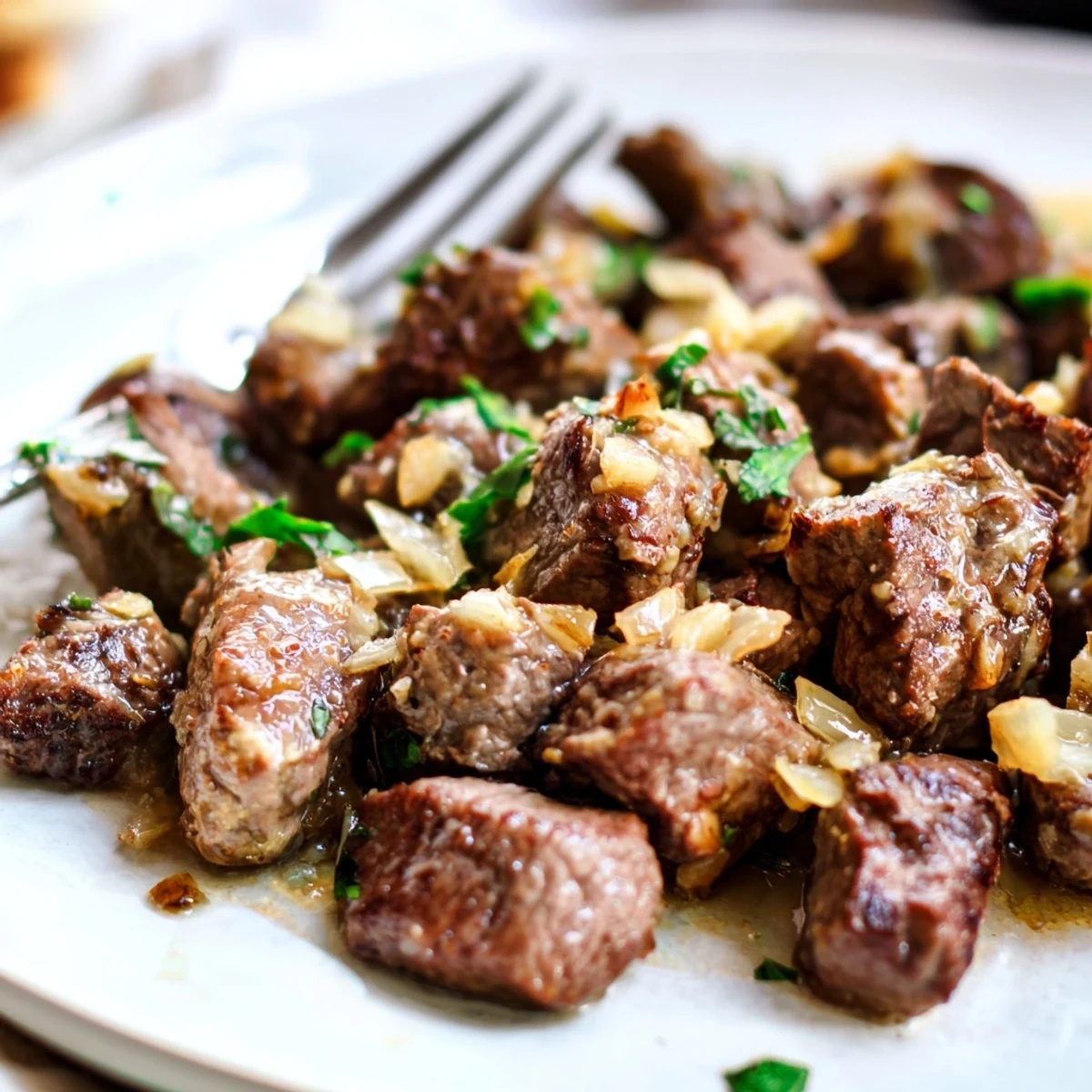 Juicy slow-cooked steak bites in savory herb broth served over fluffy mashed potatoes