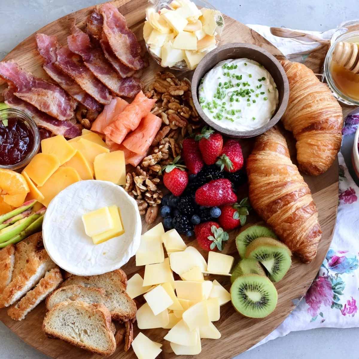Vibrant breakfast charcuterie board arranged with prosciutto, smoked salmon, brie, fresh berries, croissants, and honey