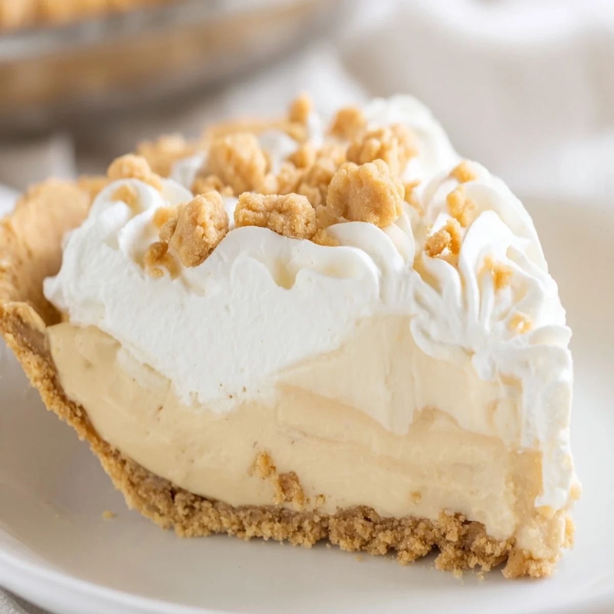 Creamy Amish peanut butter dream pie topped with fluffy whipped cream and golden crumbs