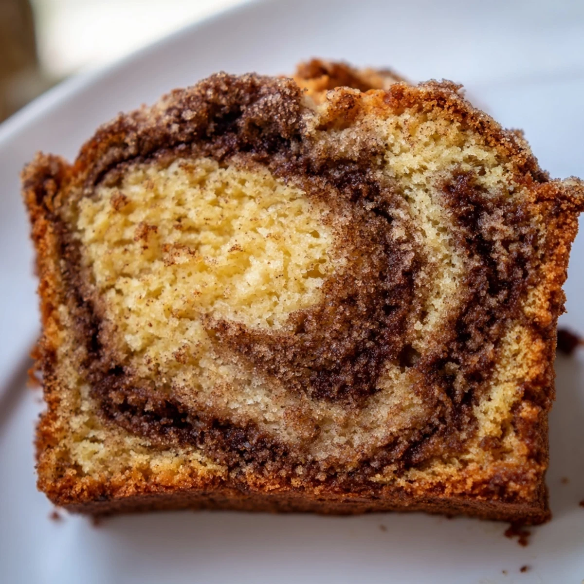 Warm slice of cinnamon sugar swirl banana bread showing golden cinnamon marbled layers