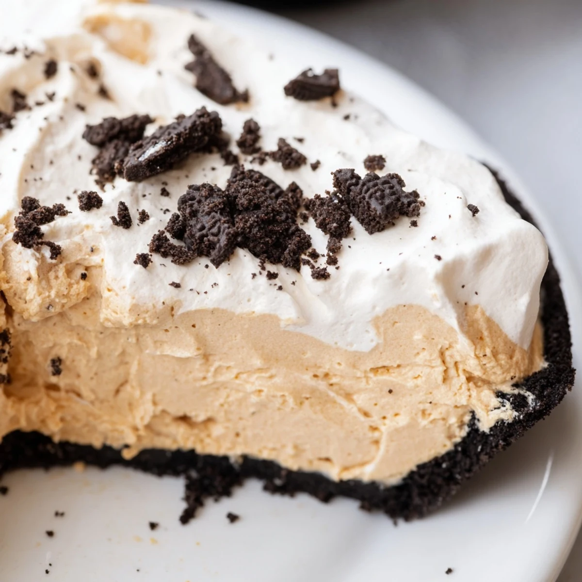 Creamy peanut butter Oreo pie with fluffy whipped topping and cookie crumbles on a dessert plate