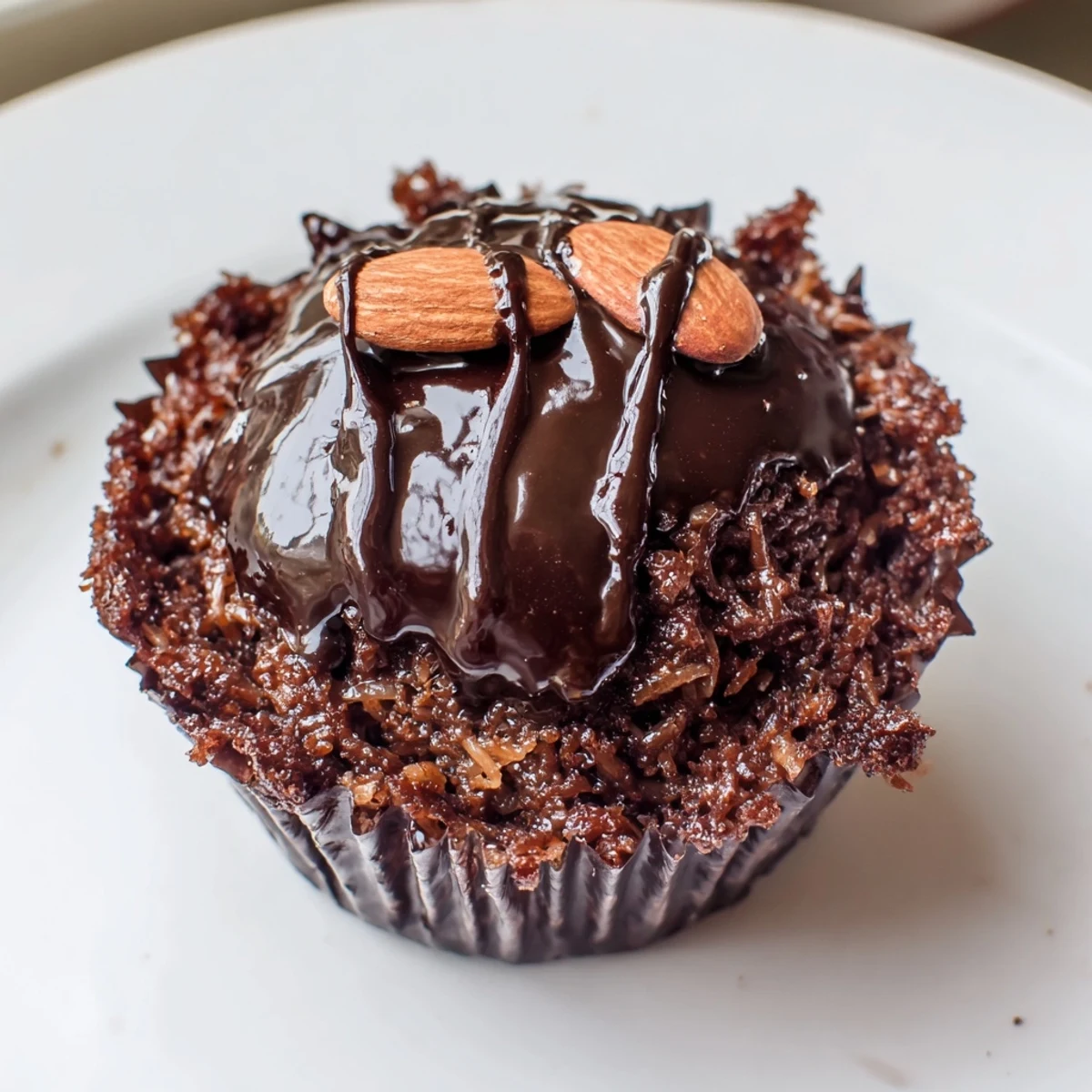 Rich flourless almond joy cupcakes drizzled with melted chocolate and topped with roasted almonds