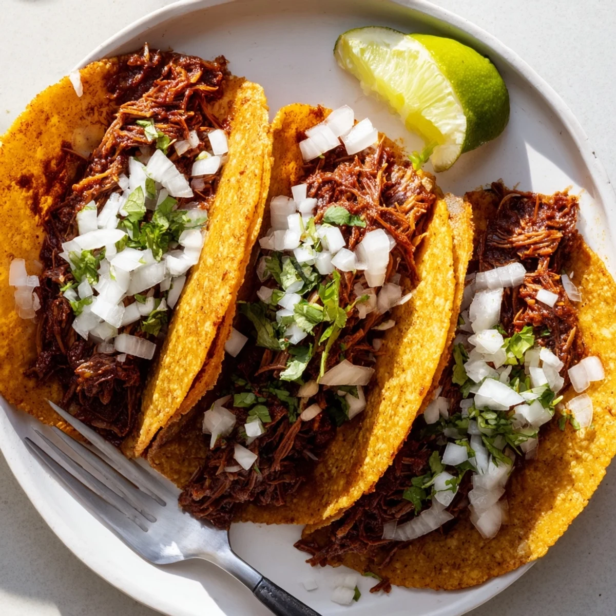 Tender shredded beef nestled in crispy slow cooker birria tacos with lime.