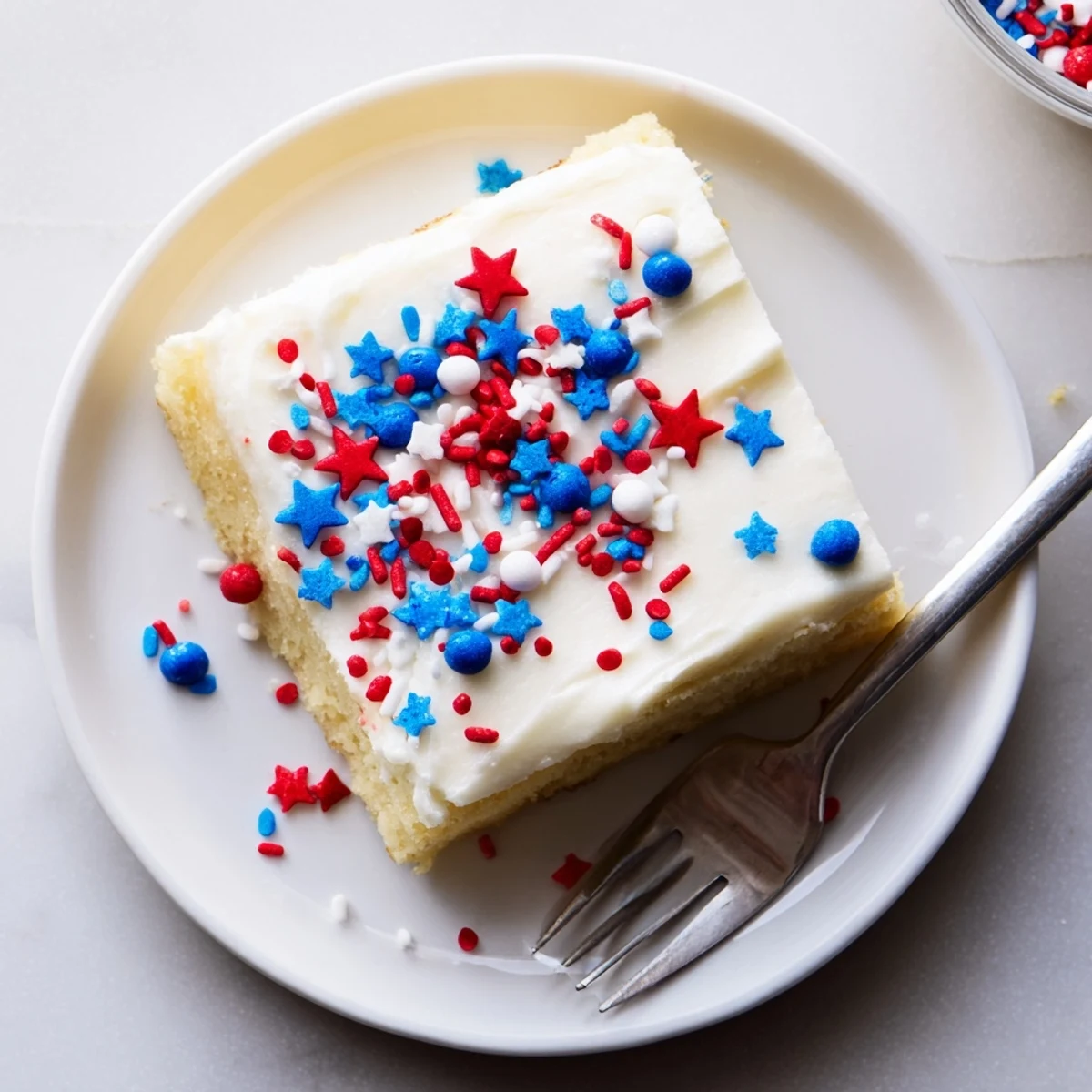 Soft 4th of July sugar cookie bars topped with creamy white vanilla frosting and colorful red white blue sprinkles for Independence Day