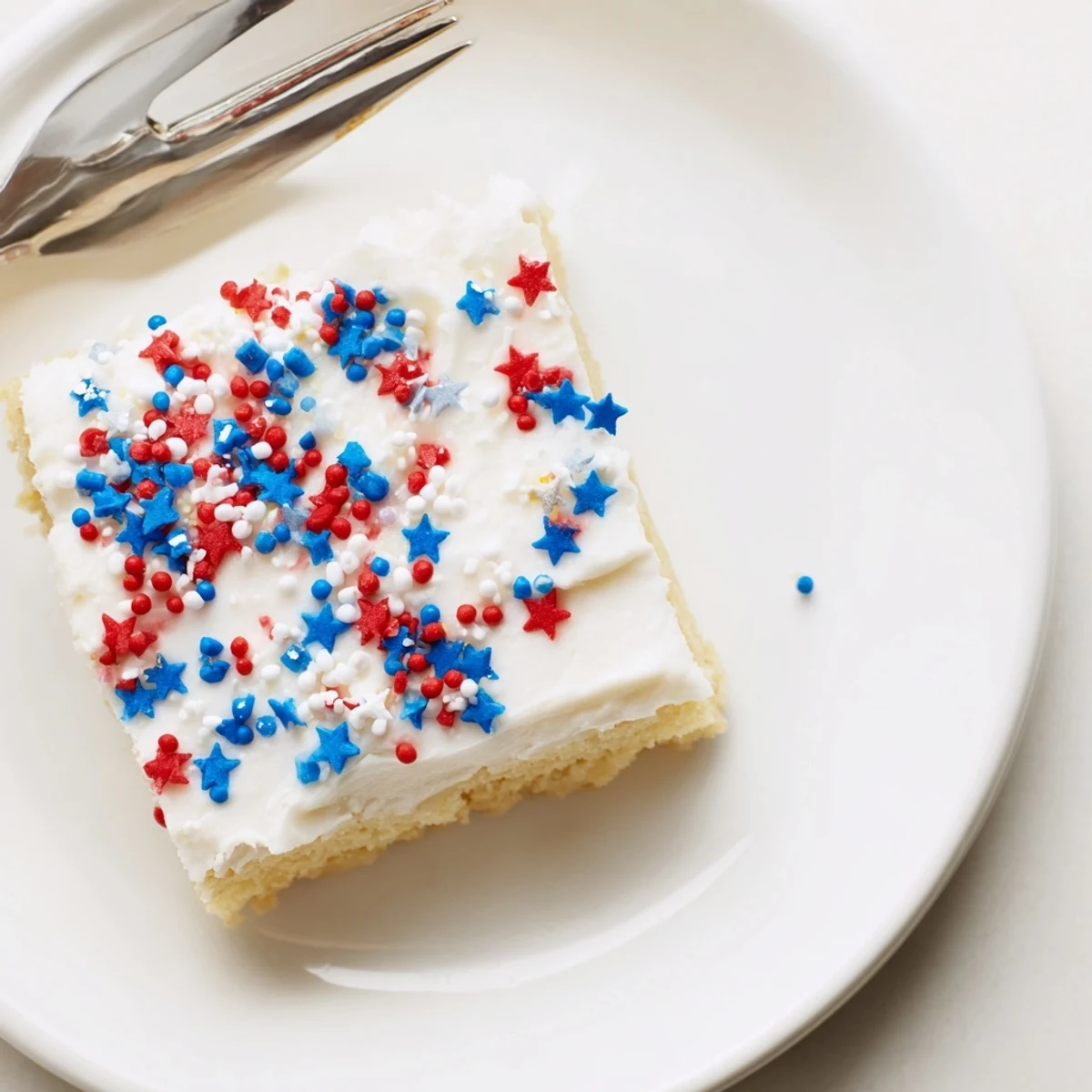 Patriotic sugar cookie bars spread with fluffy buttercream frosting and decorated with festive sprinkles perfect for your 4th of July celebration