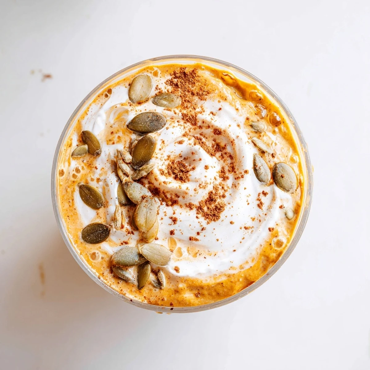 Silky pumpkin spice chia pudding drink garnished with whipped cream dusting and cinnamon for fall