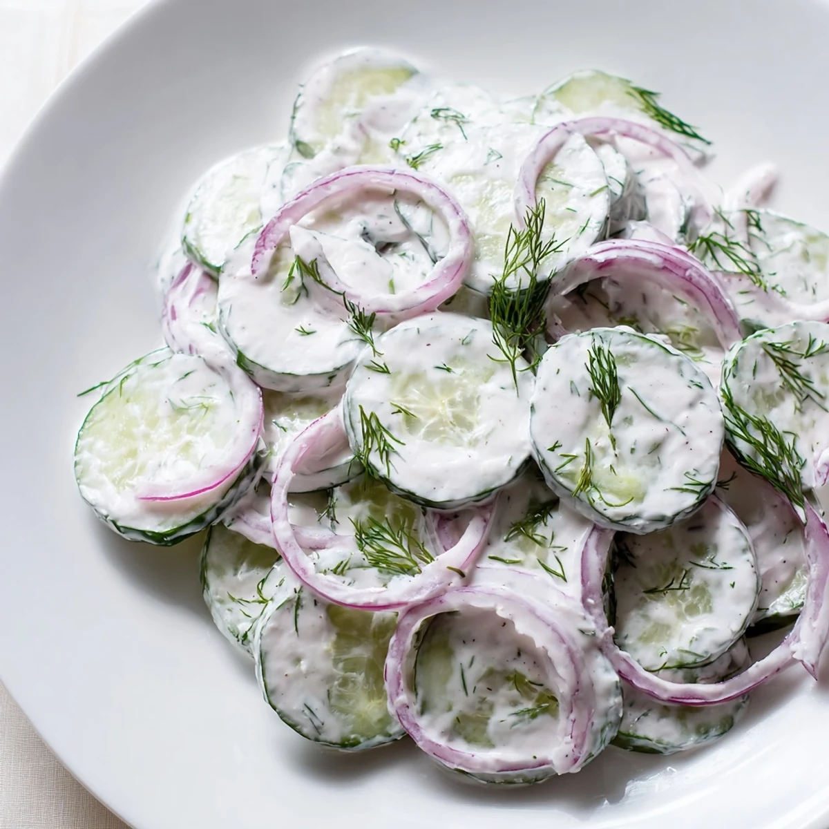 Crisp cucumber dill salad with sour cream dressing served on a rustic wooden table
