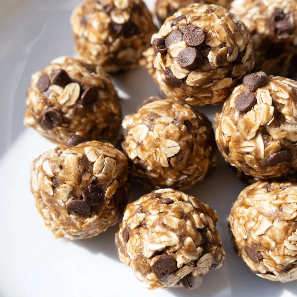 Bite-sized peanut butter energy balls featuring mini chocolate chips in a parchment-lined storage container.