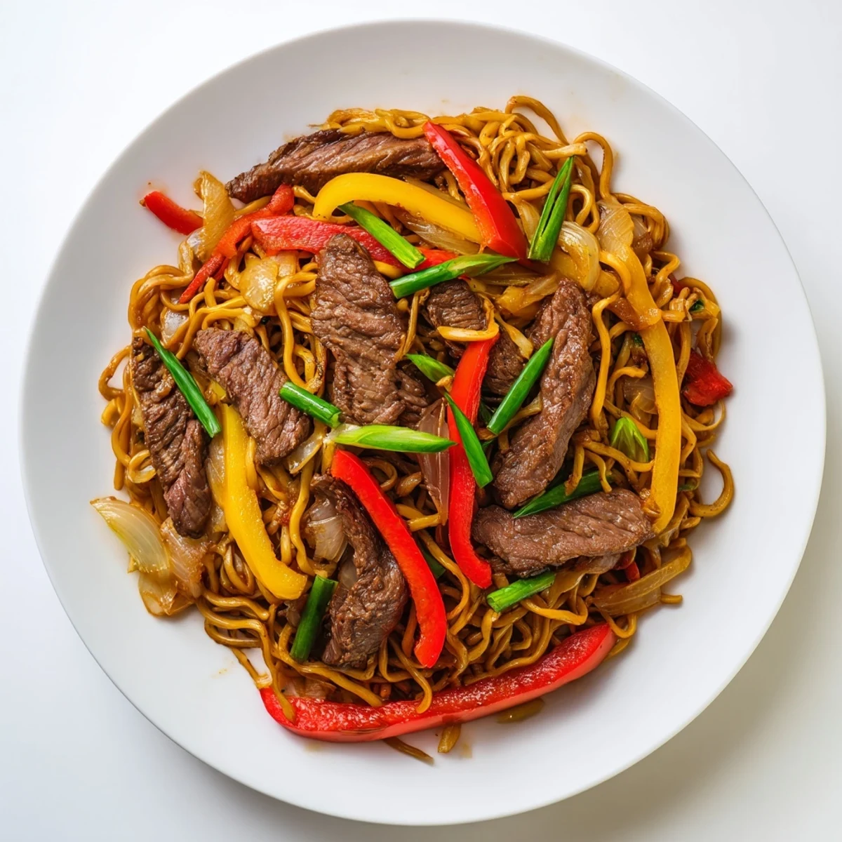 Beef chow mein with peppers and onions tossed in savory sauce in a dark wok