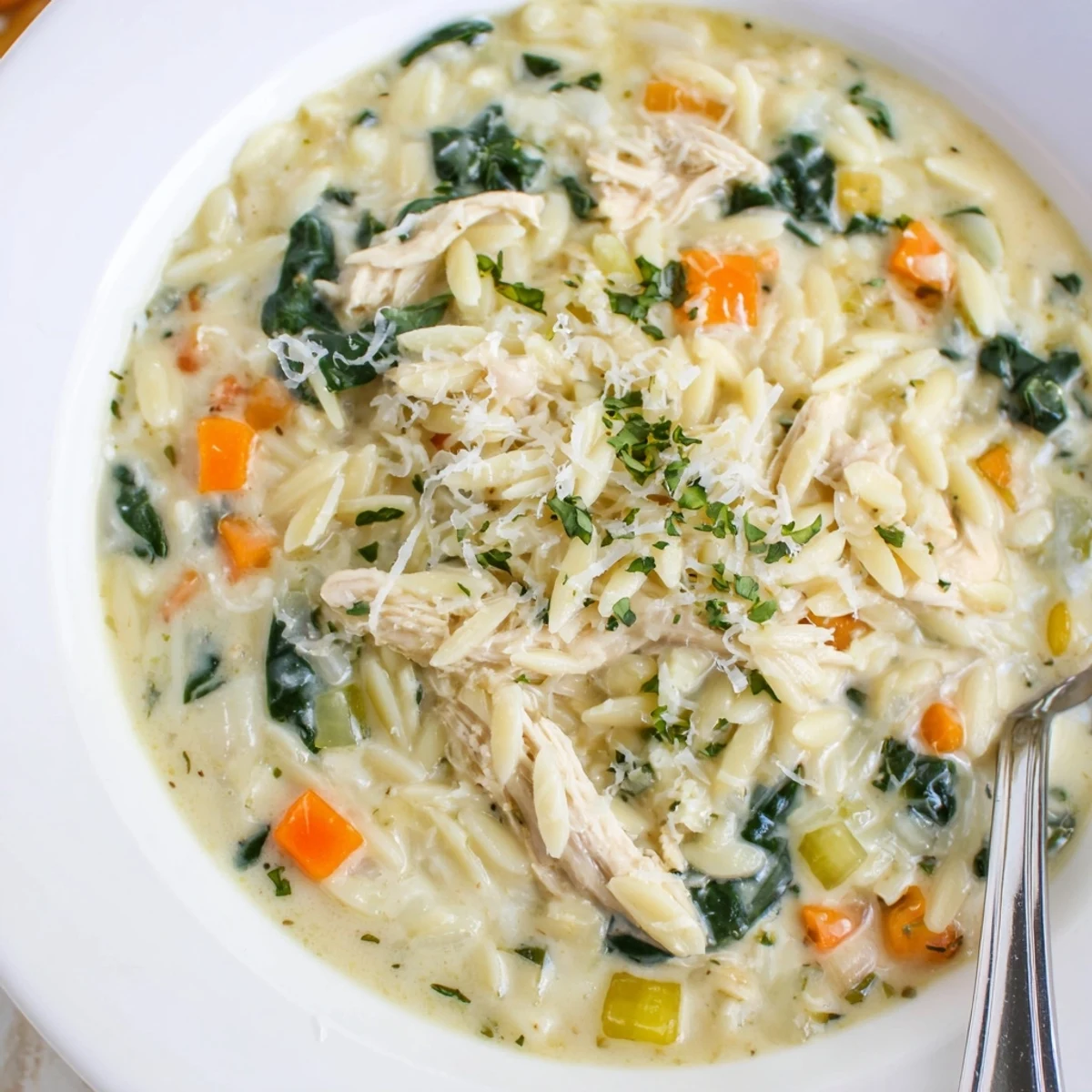 Creamy Chicken Florentine Soup With Orzo garnished with Parmesan, paired with crusty bread