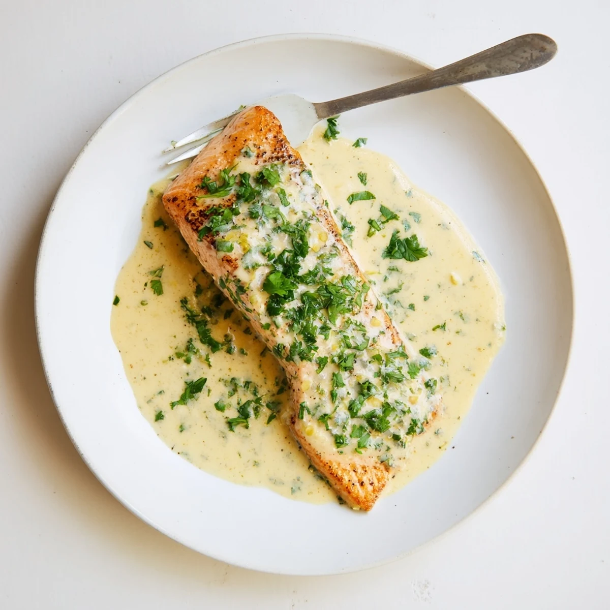 Pan-seared salmon fillets drizzled with rich lemon cream sauce and fresh parsley