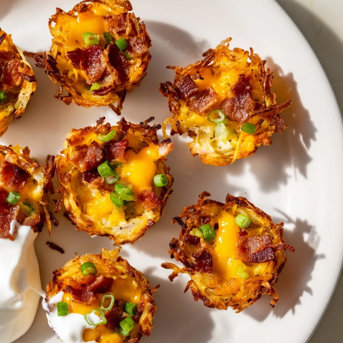 Golden crispy cheesy loaded hashbrown bites fresh from the oven with melted cheddar